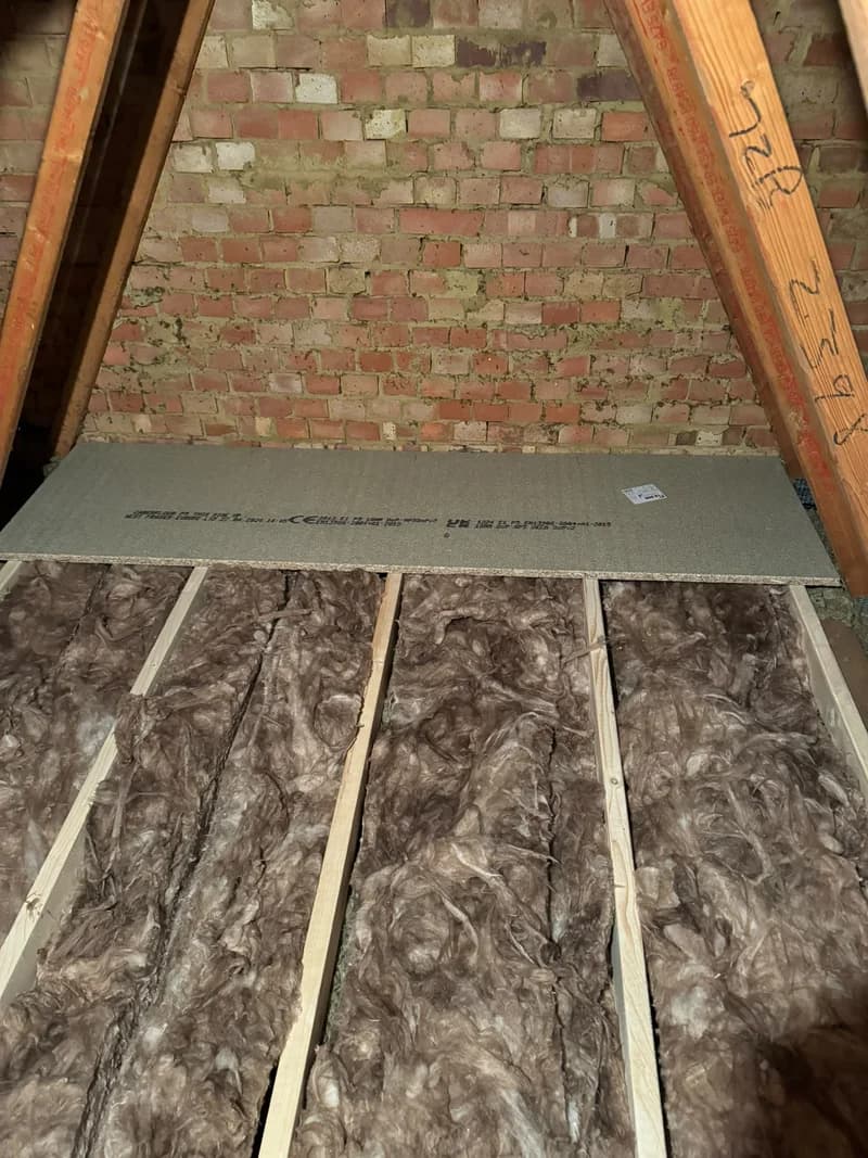 Timber supports and insulation visible beneath partially fitted loft boarding